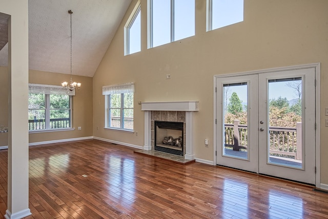 unfurnished living room with hardwood / wood-style flooring, a towering ceiling, and a healthy amount of sunlight
