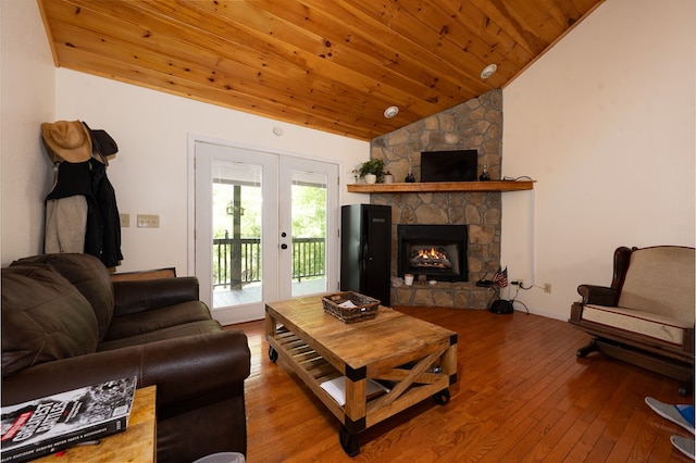 living room with vaulted ceiling, a stone fireplace, wood-type flooring, wood ceiling, and french doors