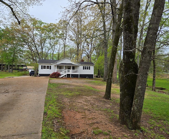 view of front of property featuring a front lawn, covered porch, and concrete driveway