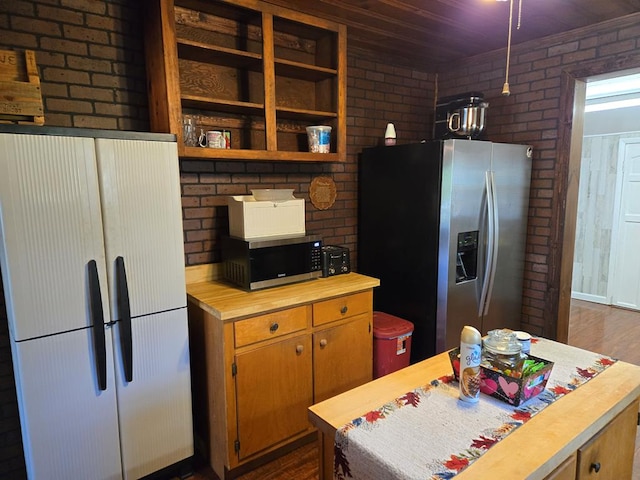 kitchen featuring brick wall, butcher block counters, and appliances with stainless steel finishes