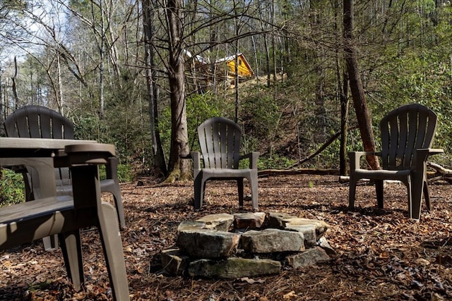 view of community with a fire pit and a view of trees