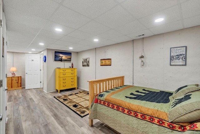 bedroom with light wood-type flooring and a paneled ceiling