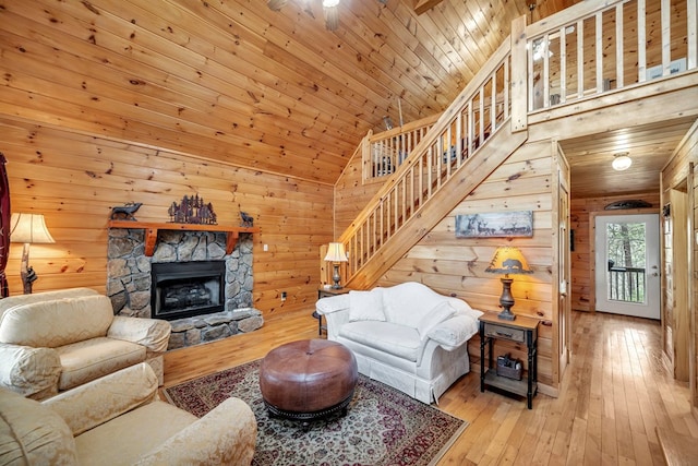 living room with high vaulted ceiling, light hardwood / wood-style floors, a stone fireplace, and wood ceiling