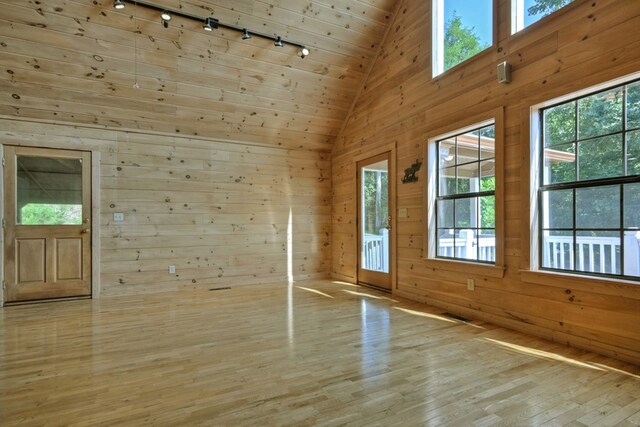 unfurnished living room with wooden ceiling, wooden walls, a fireplace, light hardwood / wood-style floors, and track lighting