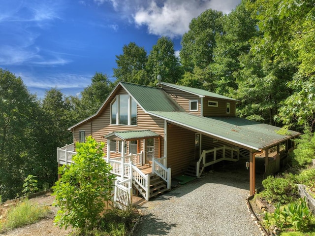 view of front facade featuring a carport, metal roof, and log veneer siding