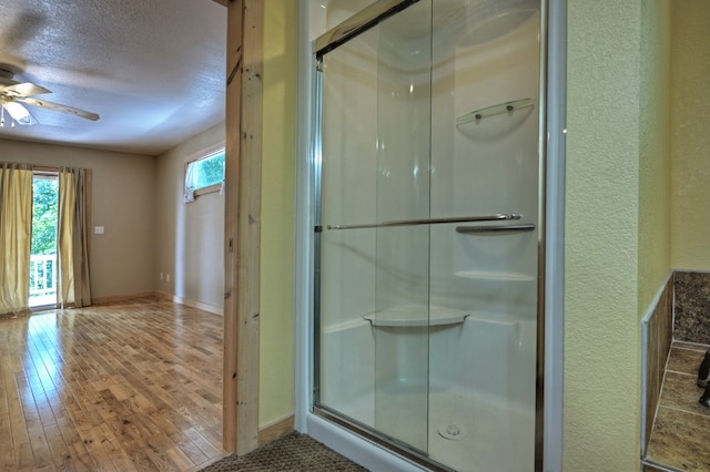 full bath featuring a shower stall, a textured ceiling, a ceiling fan, and hardwood / wood-style flooring