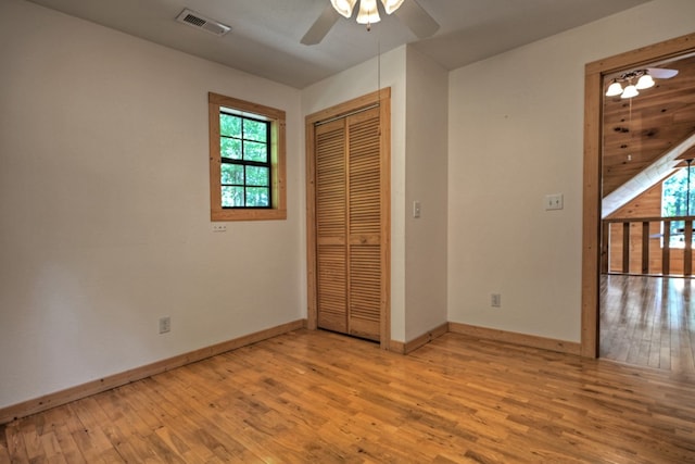 unfurnished bedroom featuring a ceiling fan, wood finished floors, visible vents, baseboards, and a closet