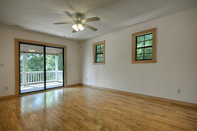 empty room featuring light wood finished floors, visible vents, and a wealth of natural light