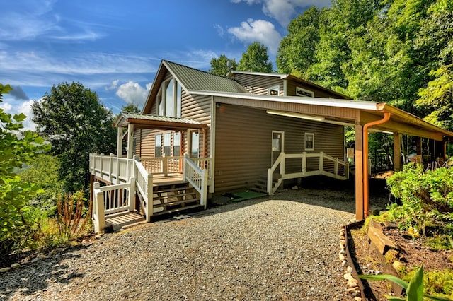 view of side of home featuring a carport, metal roof, gravel driveway, and log veneer siding