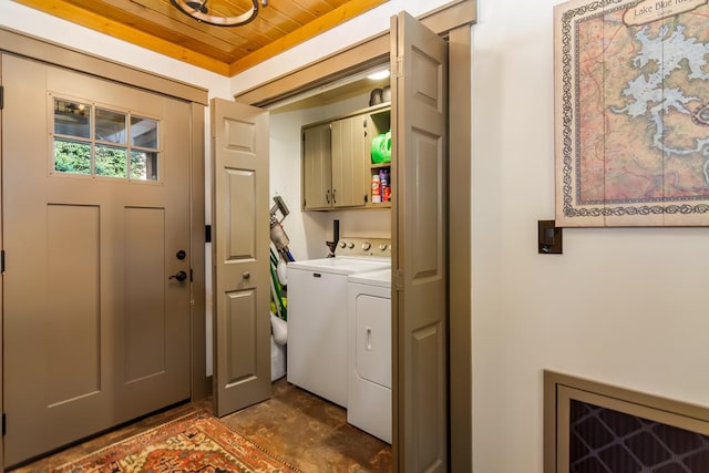 clothes washing area with wooden ceiling, washing machine and dryer, and cabinet space