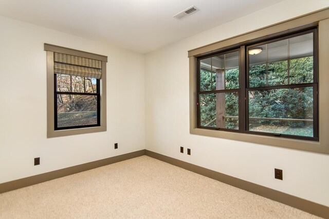 unfurnished room featuring visible vents, baseboards, carpet, and a healthy amount of sunlight