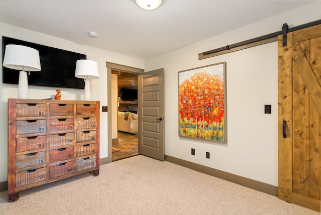 bedroom featuring a barn door, carpet, and baseboards