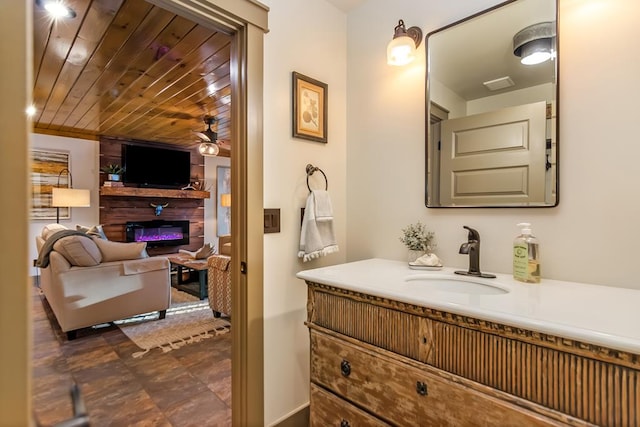 bathroom featuring a glass covered fireplace, wood ceiling, vanity, and ceiling fan