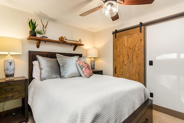 carpeted bedroom featuring a barn door, baseboards, and ceiling fan