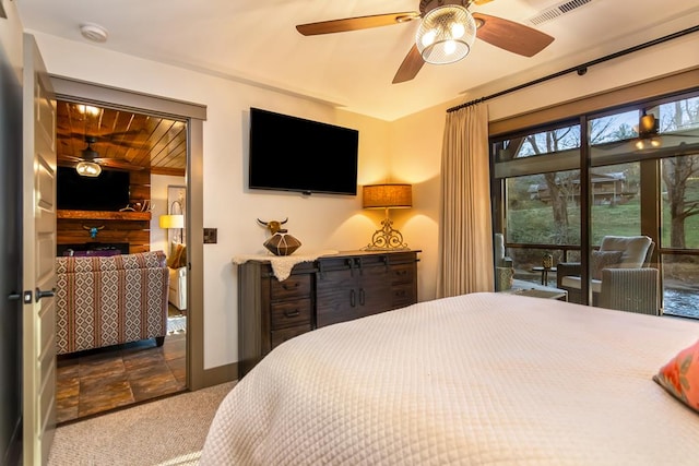 bedroom with access to exterior, visible vents, stone finish flooring, ceiling fan, and dark carpet