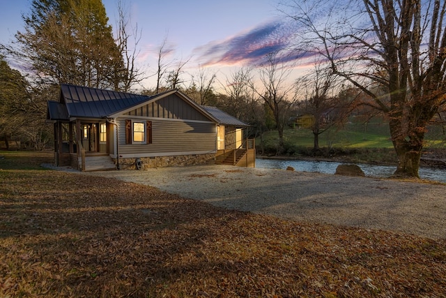 view of front of property with metal roof, board and batten siding, gravel driveway, and a standing seam roof