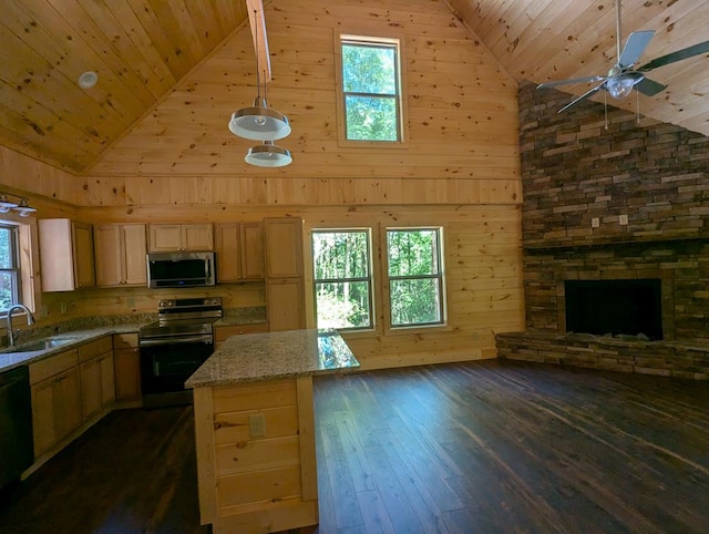 kitchen featuring dark wood-type flooring, sink, a center island, stainless steel appliances, and light stone countertops