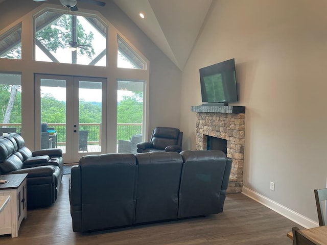 living room featuring a stone fireplace, high vaulted ceiling, dark hardwood / wood-style flooring, ceiling fan, and french doors