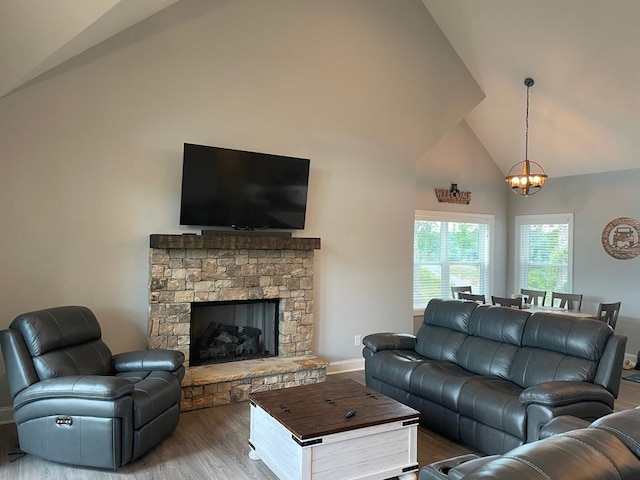 living room featuring hardwood / wood-style floors, a stone fireplace, a chandelier, and high vaulted ceiling