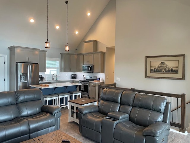 living room featuring sink, light hardwood / wood-style flooring, and high vaulted ceiling