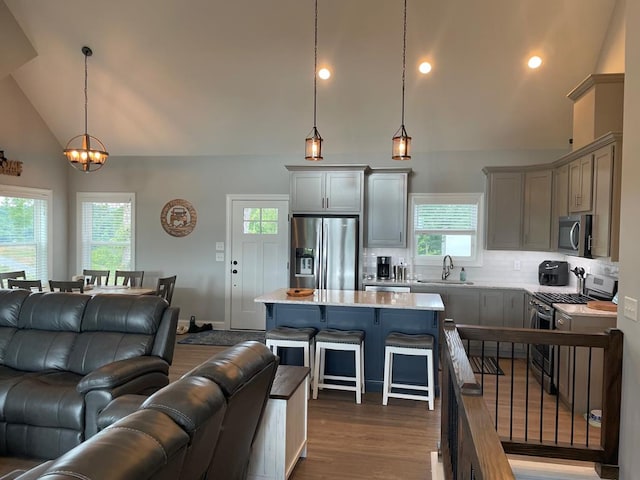 kitchen featuring a kitchen bar, sink, a center island, pendant lighting, and stainless steel appliances