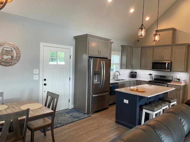 kitchen featuring a kitchen island, appliances with stainless steel finishes, sink, a breakfast bar area, and hanging light fixtures