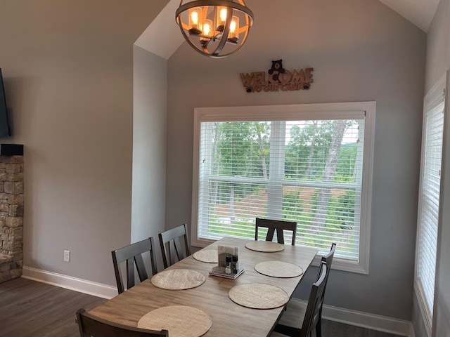 dining room with lofted ceiling, a healthy amount of sunlight, dark hardwood / wood-style floors, and a chandelier