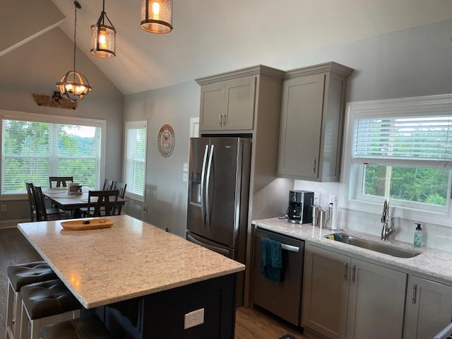 kitchen with sink, gray cabinetry, decorative light fixtures, appliances with stainless steel finishes, and light stone countertops