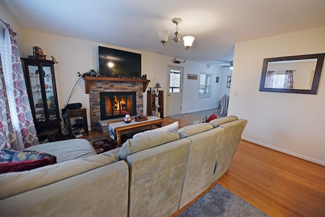 living room featuring ceiling fan with notable chandelier, a fireplace, and light hardwood / wood-style flooring