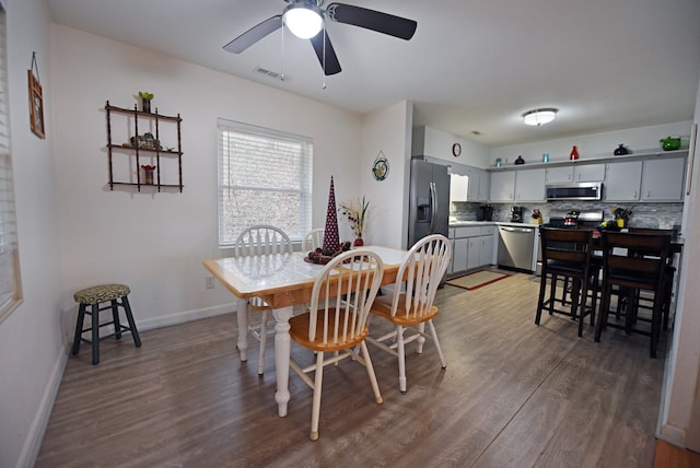 dining space with ceiling fan and dark wood-type flooring