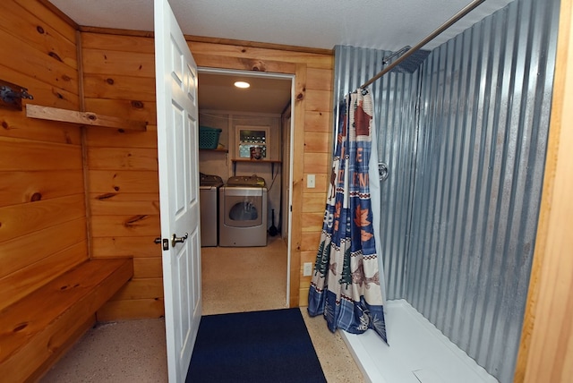 bathroom with a shower with shower curtain, independent washer and dryer, and wooden walls