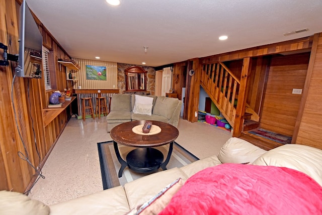 living room featuring a textured ceiling and wooden walls