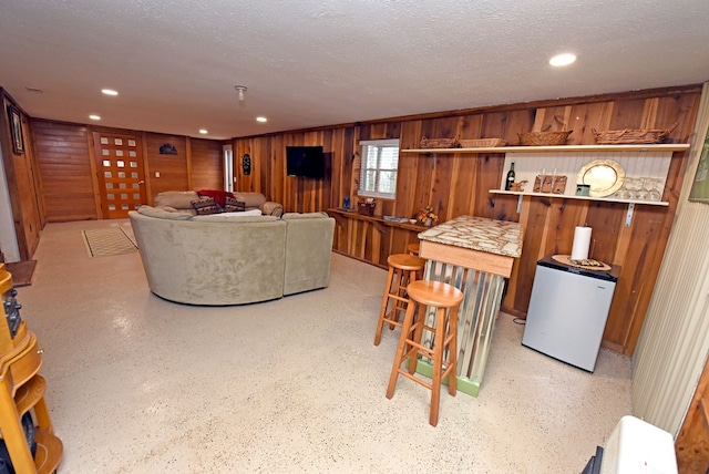 living room with wooden walls and a textured ceiling