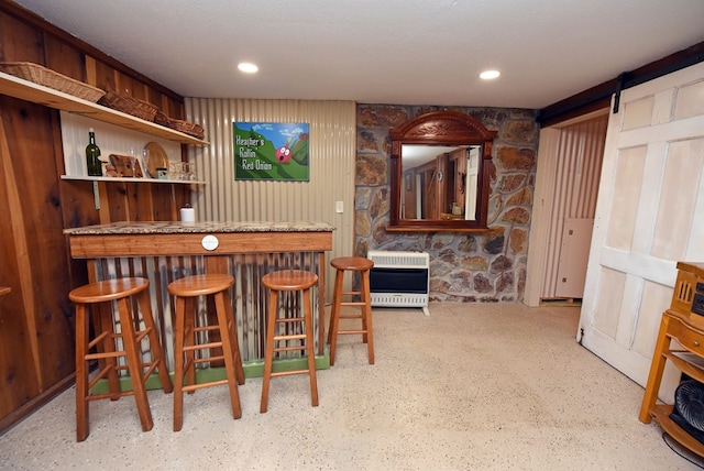 bar featuring a barn door, heating unit, and wooden walls