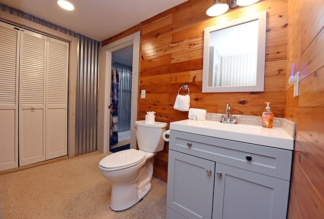 bathroom featuring vanity, toilet, walk in shower, and wooden walls