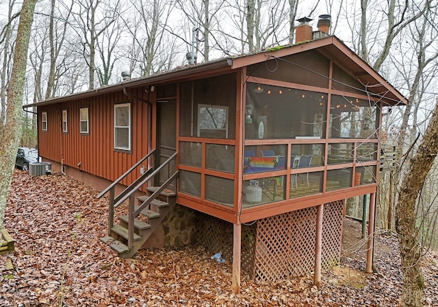 rear view of property featuring a sunroom and cooling unit