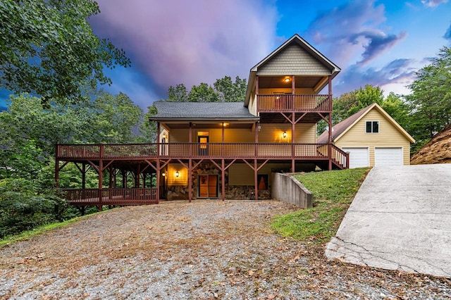 rustic home featuring a garage, a wooden deck, a shingled roof, and an outbuilding