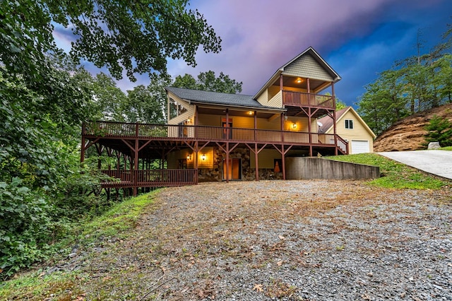 view of front of home with a deck, driveway, stone siding, and an attached garage