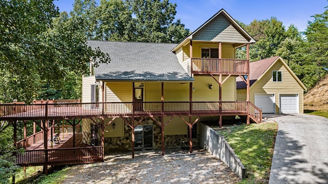 view of front facade featuring a garage, roof with shingles, an outdoor structure, and a deck