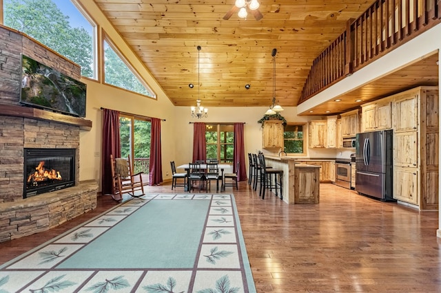 kitchen featuring appliances with stainless steel finishes, a fireplace, wood finished floors, and wood ceiling