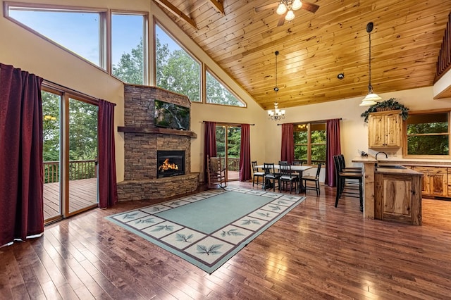 living room with lofted ceiling, a stone fireplace, wooden ceiling, dark wood-type flooring, and an inviting chandelier