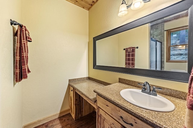 bathroom featuring a textured wall, baseboards, wood finished floors, and vanity