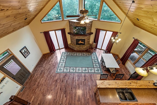 living area with high vaulted ceiling, a fireplace, wood finished floors, and wooden ceiling