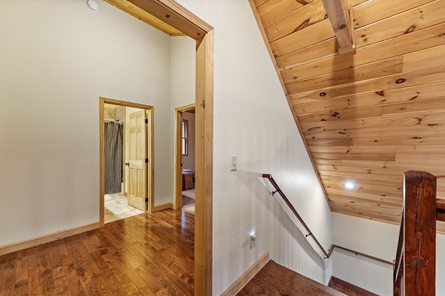 staircase with wood-type flooring, wooden ceiling, and baseboards