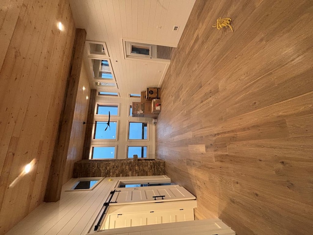 interior space with white cabinetry, wood ceiling, and wood walls