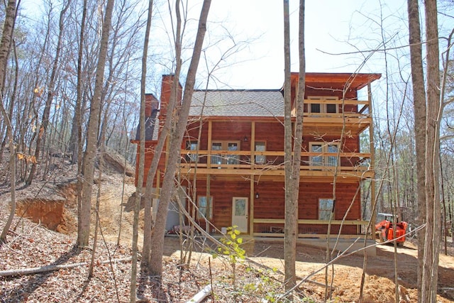 back of house featuring a wooden deck, a chimney, and a shingled roof