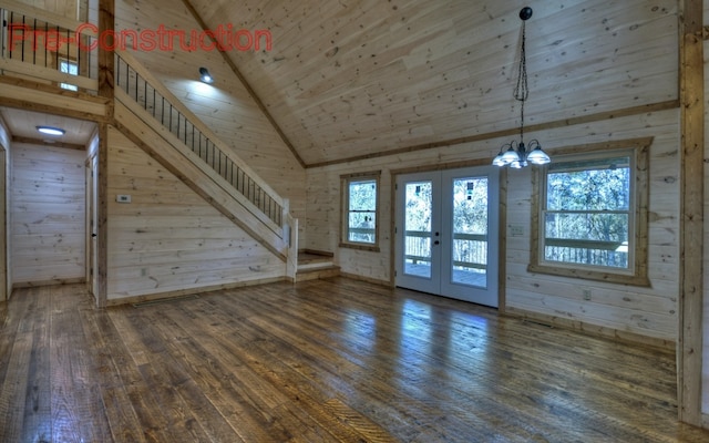 unfurnished living room with hardwood / wood-style floors, stairs, wood ceiling, french doors, and wood walls