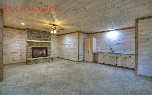 unfurnished living room featuring wood walls, wood ceiling, concrete flooring, a fireplace, and a ceiling fan