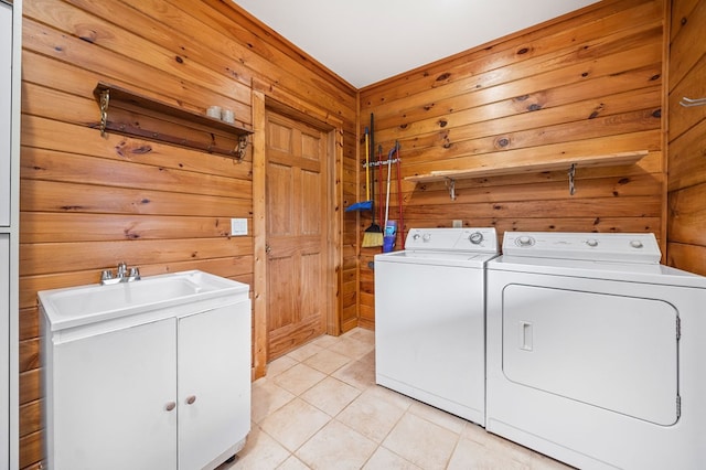 clothes washing area with cabinets, sink, independent washer and dryer, light tile patterned floors, and wooden walls