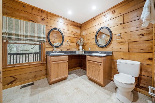 bathroom featuring toilet, vanity, and wood walls